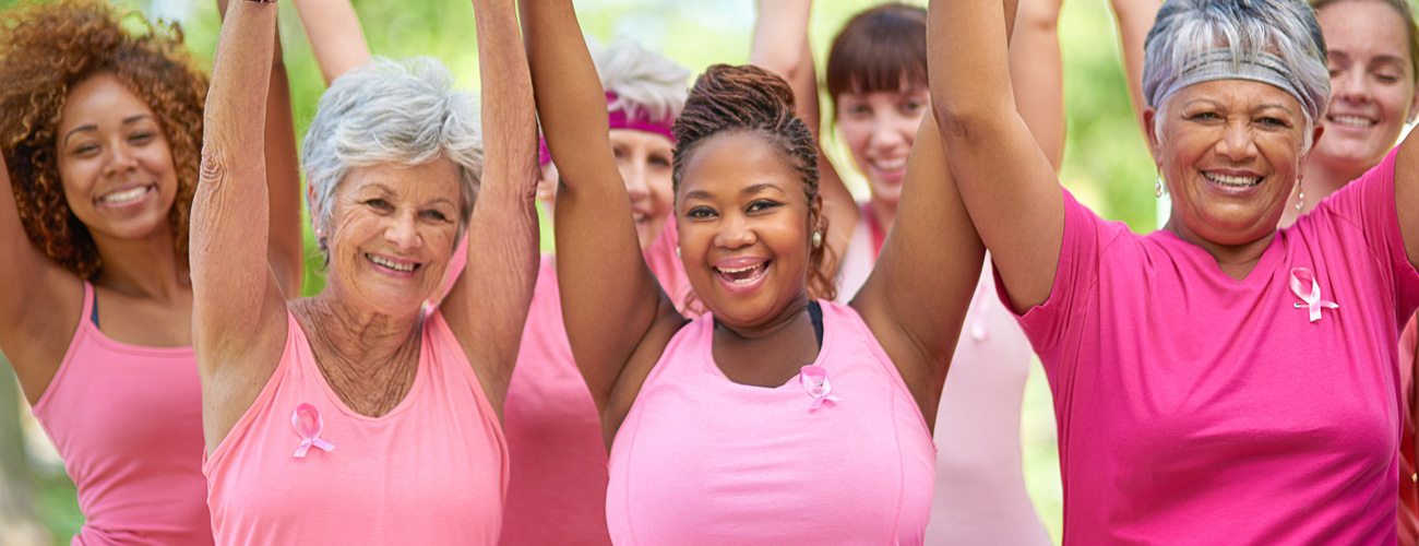 A group of women raising their hands for Breast Cancer awareness.